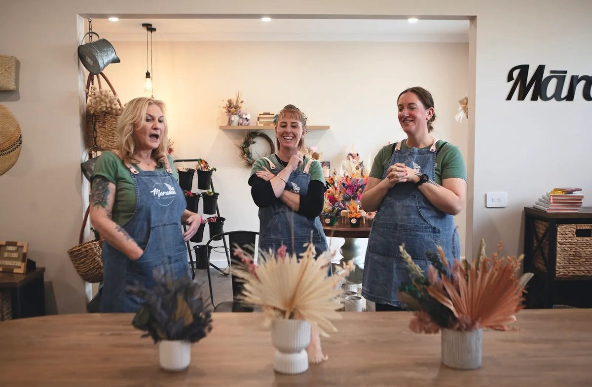 The team in the studio with three dried flower arrangements
