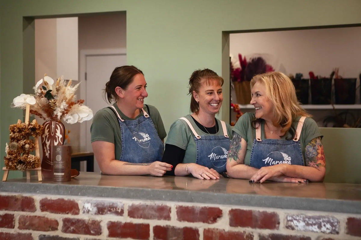 Three of the Marama team laughing behind the studio counter