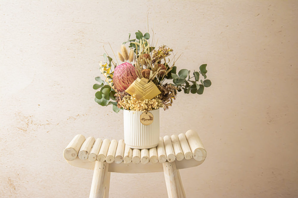 Dried flower vase arrangement with eucalyptus on a wooden stool